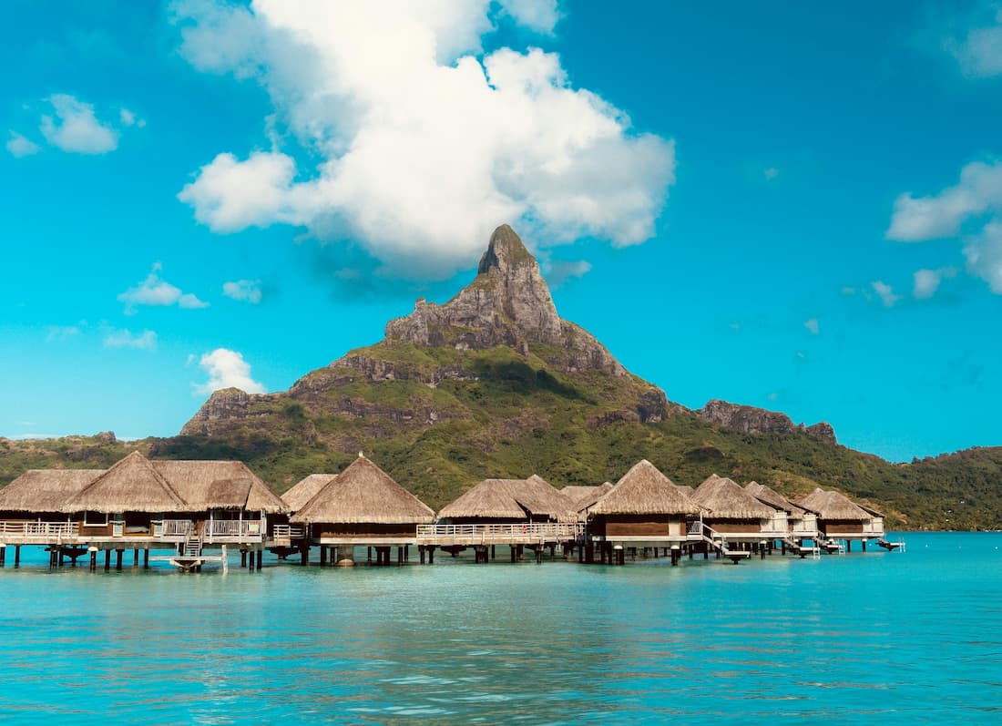 Bungalow overwater en Bora Bora — el icono del viaje de lujo a Tahití Bungalow overwater sobre la laguna turquesa de Bora Bora en la Polinesia Francesa con el Monte Otemanu al fondo