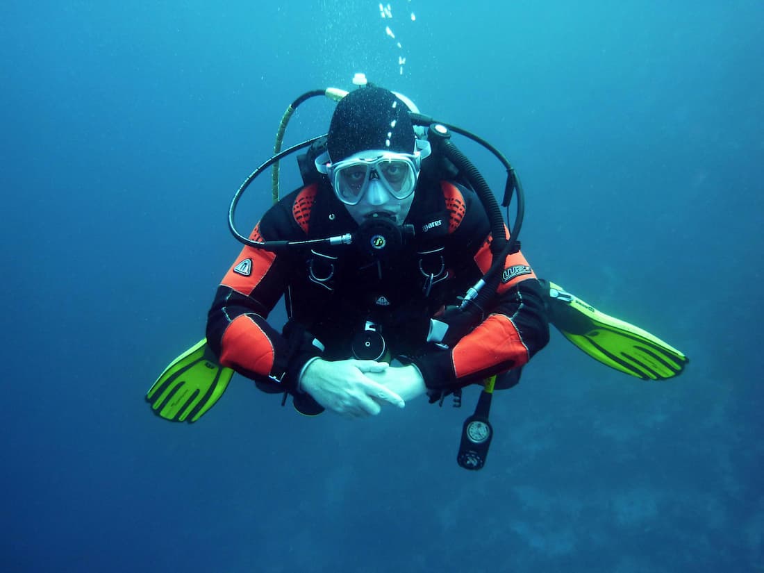 Submarinista realizando el curso PADI Open Water en las aguas del Mediterráneo en Cambrils con fauna marina al fondo