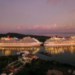 Dos cruceros de lujo amarrados en puerto de noche con luces reflejadas en el agua