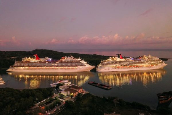 Dos cruceros de lujo amarrados en puerto de noche con luces reflejadas en el agua