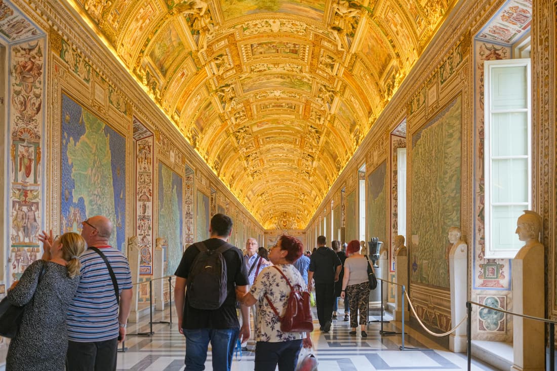 Galería interior Vaticano techo decorado visitantes Roma viajes culturales Galería interior de los Museos Vaticanos con techo decorado y visitantes contemplando el arte en Roma