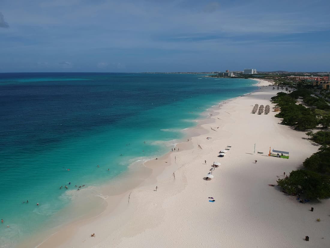 Eagle Beach Aruba al atardecer con palmeras inclinadas y aguas turquesas del Caribe