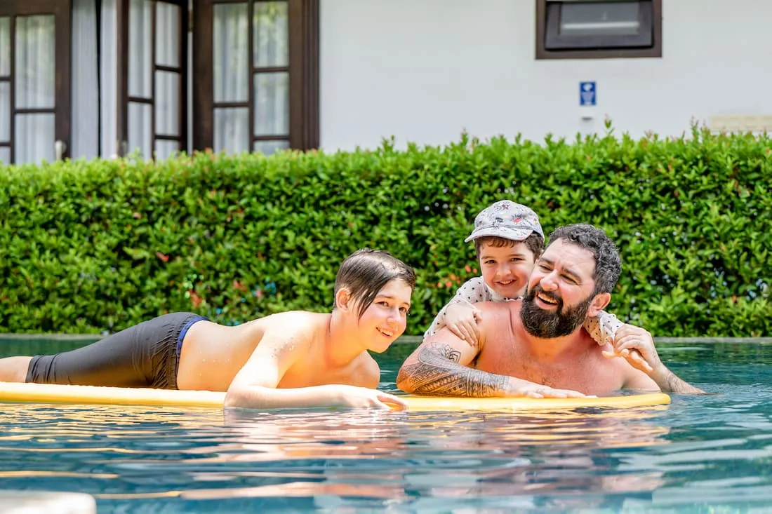 Familia con niños disfrutando de piscina privada en villa de vacaciones en verano en España