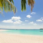 Playa blanca con mar turquesa y botes de pescadores anclados en aguas de Maldivas