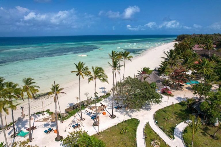 Larga playa casi desierta con palmeras frente al mar turquesa transparente en Zanzíbar Tanzania