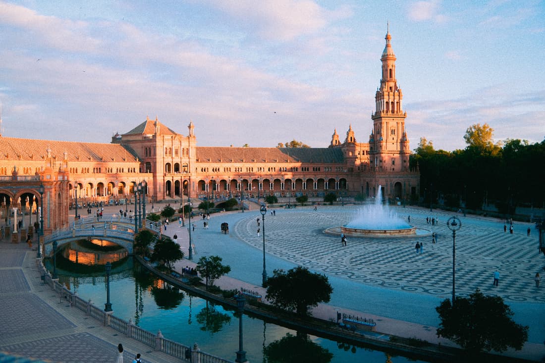 Plaza de España de Sevilla al atardecer con fuentes azulejos y arquitectura regionalista andaluza