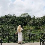Mujer de espaldas con vestido blanco contemplando las terrazas de arroz de Tegalalang desde terraza con vistas en Ubud Bali