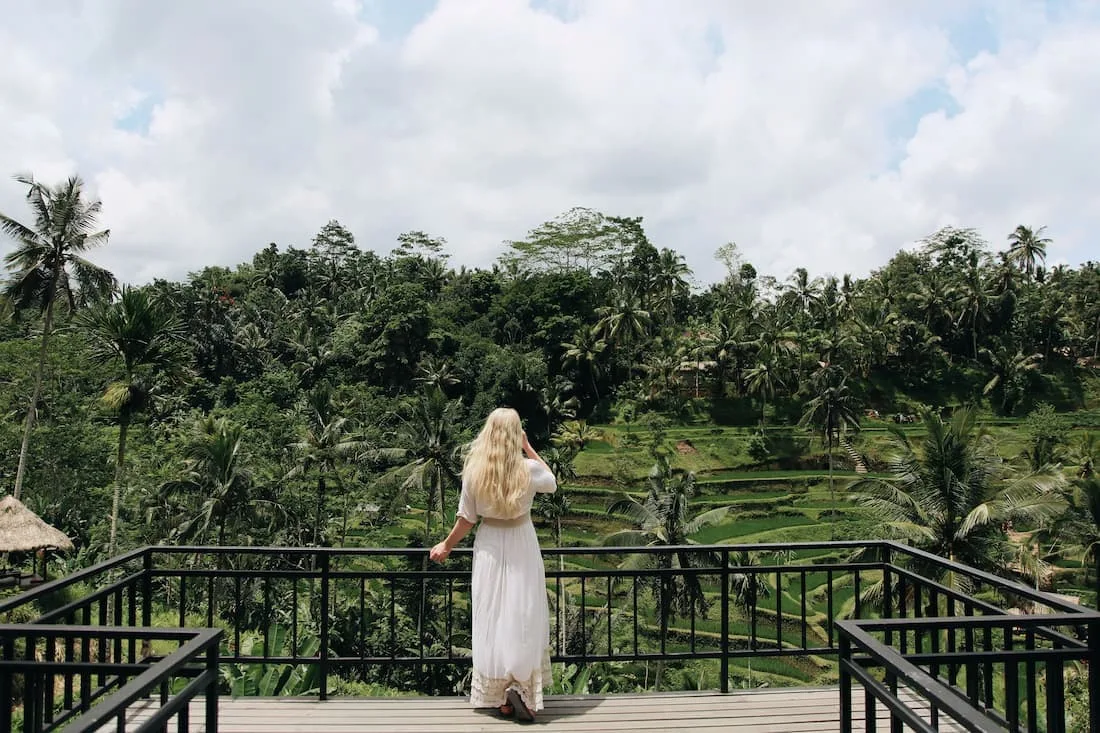 Mujer de espaldas con vestido blanco contemplando las terrazas de arroz de Tegalalang desde terraza con vistas en Ubud Bali