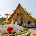 Templo budista dorado con decoración intrincada y palmeras en Chiang Mai Tailandia ciudad del norte