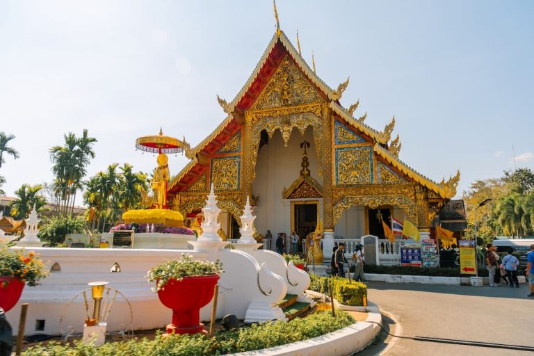 Templo budista dorado con decoración intrincada y palmeras en Chiang Mai Tailandia ciudad del norte