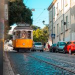 Tranvía 28 amarillo recorriendo callejuela empedrada de Lisboa Portugal símbolo del turismo lento europeo