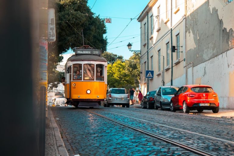 Tranvía 28 amarillo recorriendo callejuela empedrada de Lisboa Portugal símbolo del turismo lento europeo