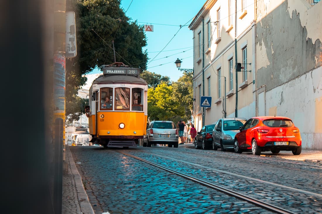 Tranvía 28 amarillo recorriendo callejuela empedrada de Lisboa Portugal símbolo del turismo lento europeo