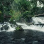 Cascada de aguas blancas con puentes de madera rodeada de selva tropical en Costa Rica ecoturismo de lujo naturaleza
