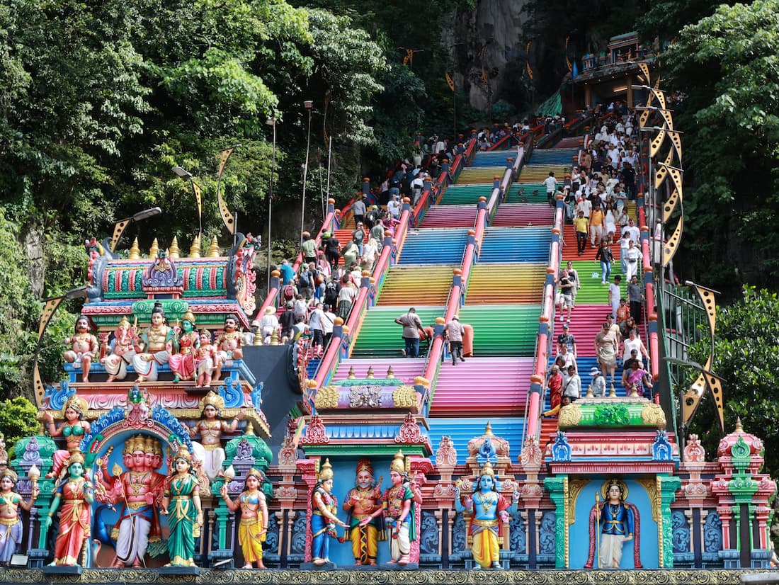 Escaleras de colores arcoíris de las Cuevas de Batu con esculturas hindúes y visitantes subiendo cerca de Kuala Lumpur Malaysia