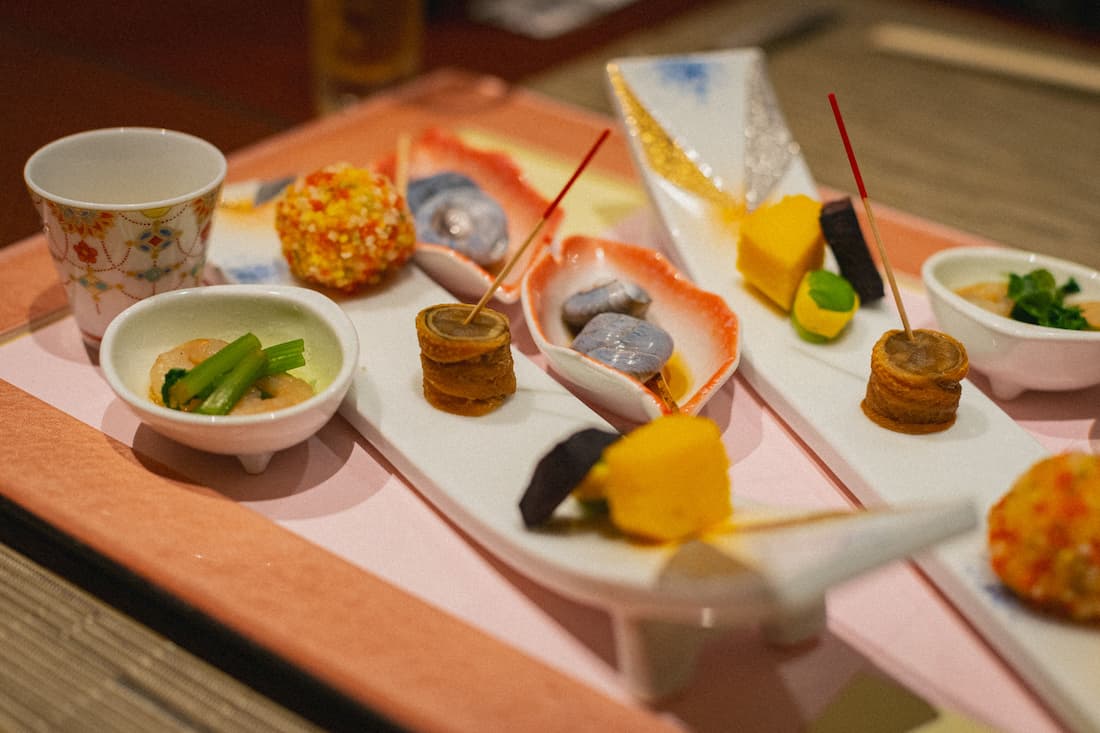 Kaiseki japonés con múltiples pequeños platos en vajilla de cerámica artesanal evocando la cena de lujo a bordo del Seven Stars Kyushu