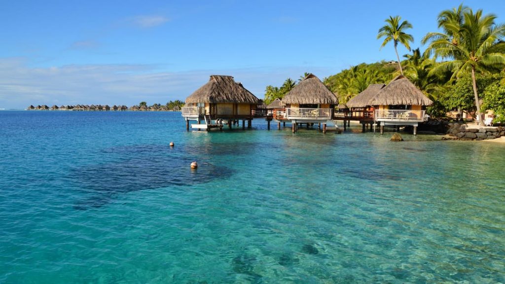 Overwater bungalows con techos de paja sobre laguna turquesa cristalina en Bora Bora Polinesia Francesa luna de miel