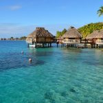 Overwater bungalows con techos de paja sobre laguna turquesa cristalina en Bora Bora Polinesia Francesa luna de miel