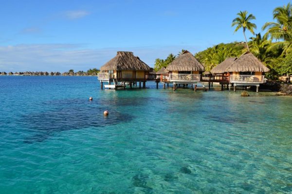 Overwater bungalows con techos de paja sobre laguna turquesa cristalina en Bora Bora Polinesia Francesa luna de miel
