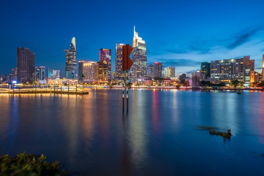 Skyline nocturno de Ho Chi Minh reflejado en el río Saigón con rascacielos iluminados Vietnam