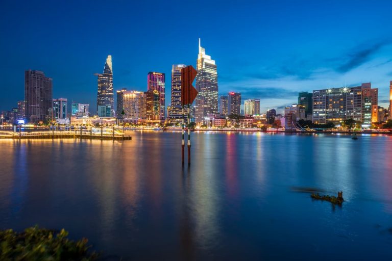Skyline nocturno de Ho Chi Minh reflejado en el río Saigón con rascacielos iluminados Vietnam