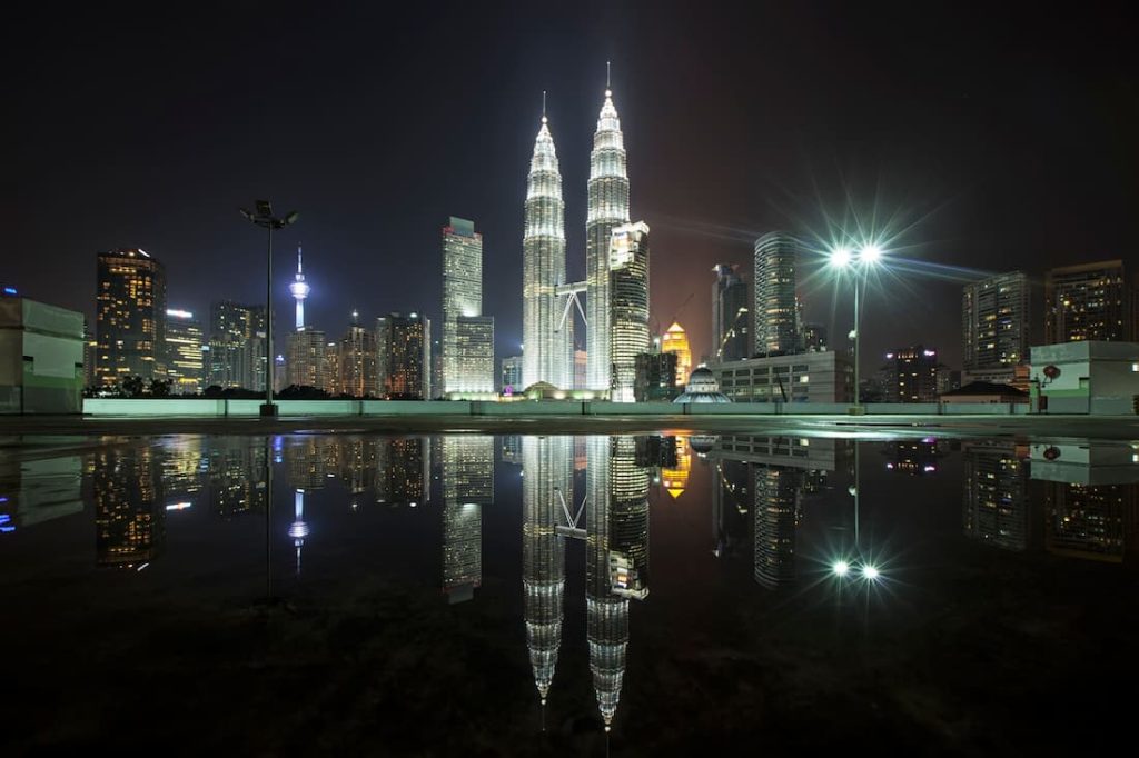 Torres Petronas iluminadas de noche reflejadas en el agua con el skyline de Kuala Lumpur Malaysia