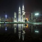 Torres Petronas iluminadas de noche reflejadas en el agua con el skyline de Kuala Lumpur Malaysia