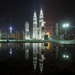 Torres Petronas iluminadas de noche reflejadas en el agua con el skyline de Kuala Lumpur Malaysia