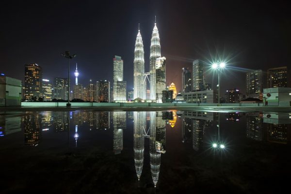 Torres Petronas iluminadas de noche reflejadas en el agua con el skyline de Kuala Lumpur Malaysia