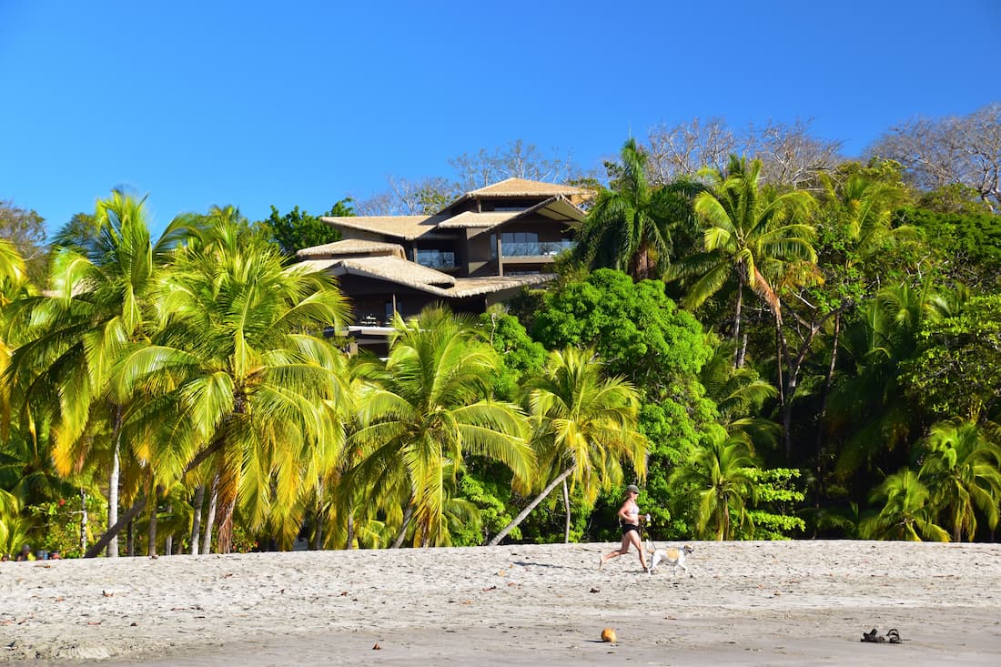 Villa de lujo con techo de paja entre palmeras tropicales sobre playa de arena blanca en Costa Rica ecolodge Pacífico