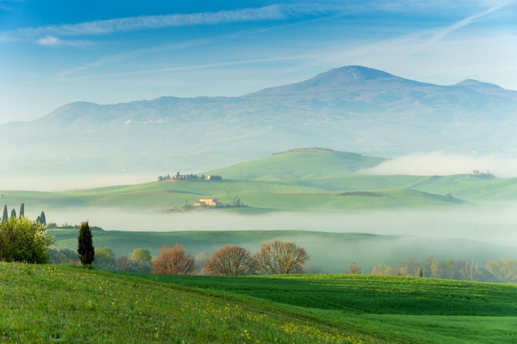 Colinas verdes del Val d'Orcia envueltas en niebla al amanecer, Toscana, Italia