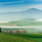 Colinas verdes del Val d'Orcia envueltas en niebla al amanecer, Toscana, Italia